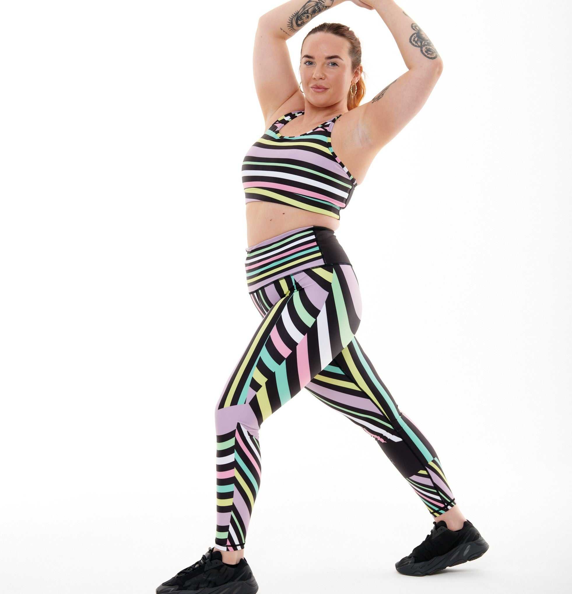 Aso-Oke Pastel Vibrant Leggings with striped pattern and pastel colors, modeled by a person stretching.
