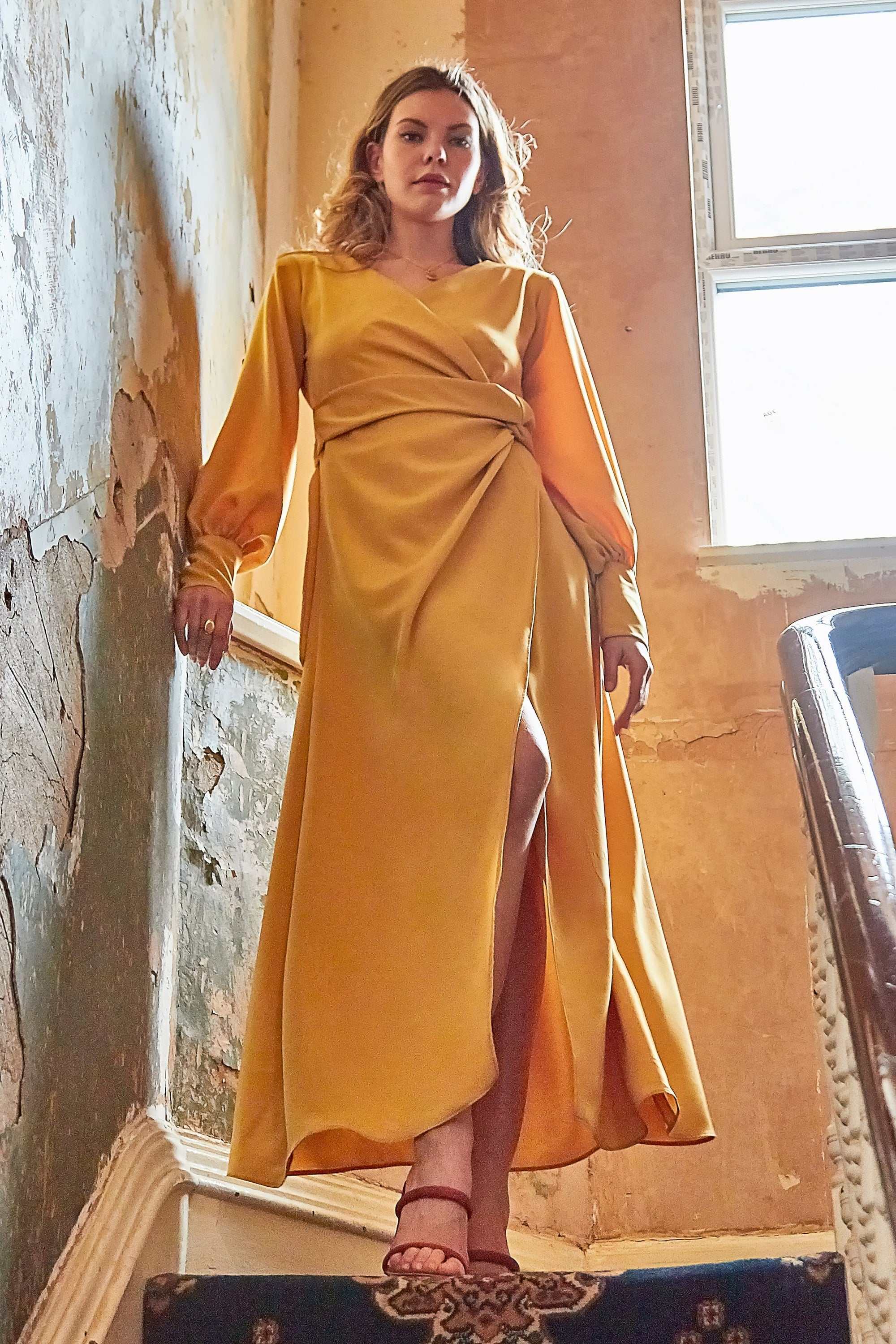 Vintage-inspired mustard wrap dress with balloon sleeves, tie waist, and side slit.