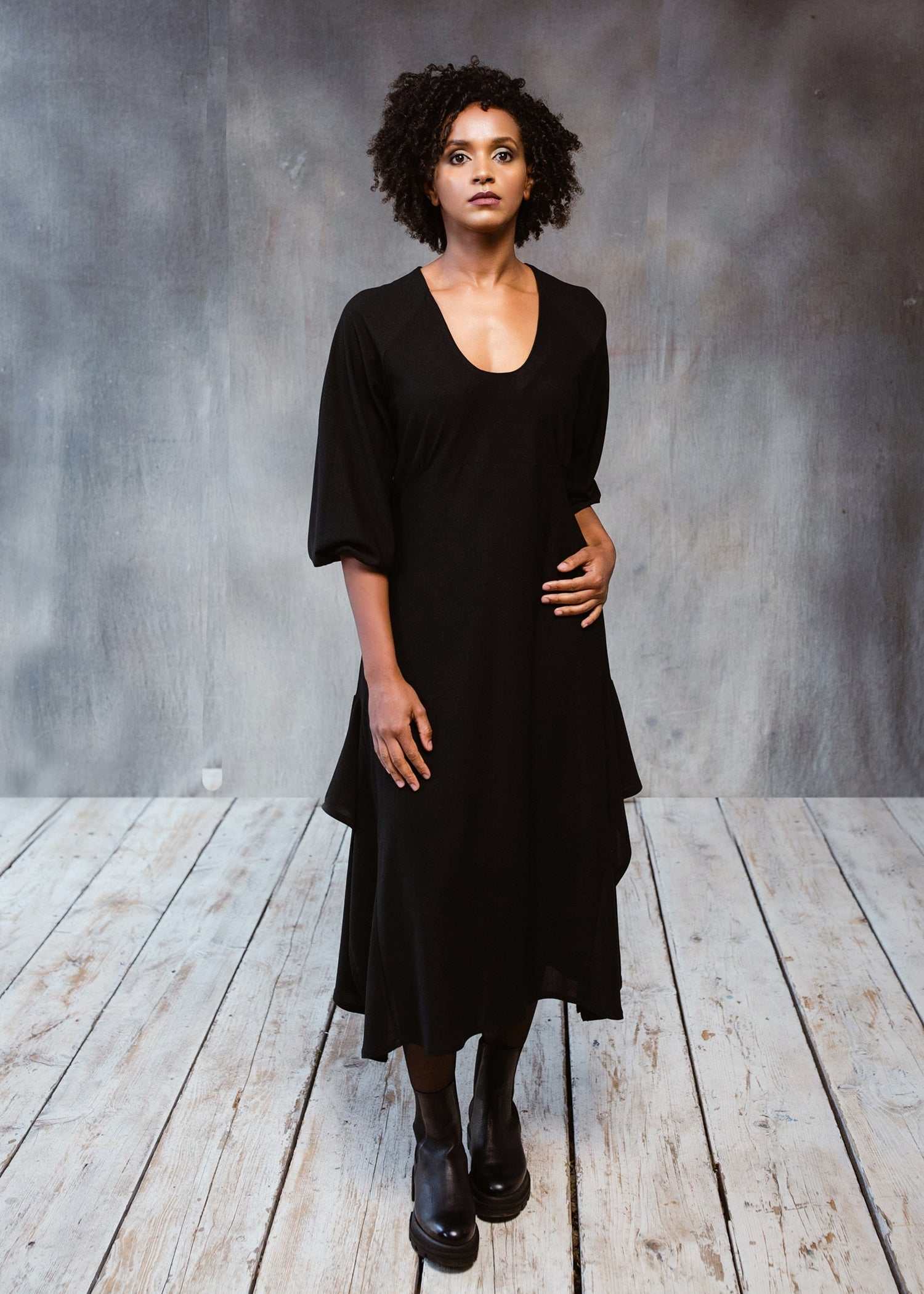 Black dress with 3/4 sleeves and side frill, worn by a model.