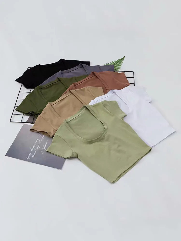 U-neck crop tops in various solid colors neatly arranged on a surface.