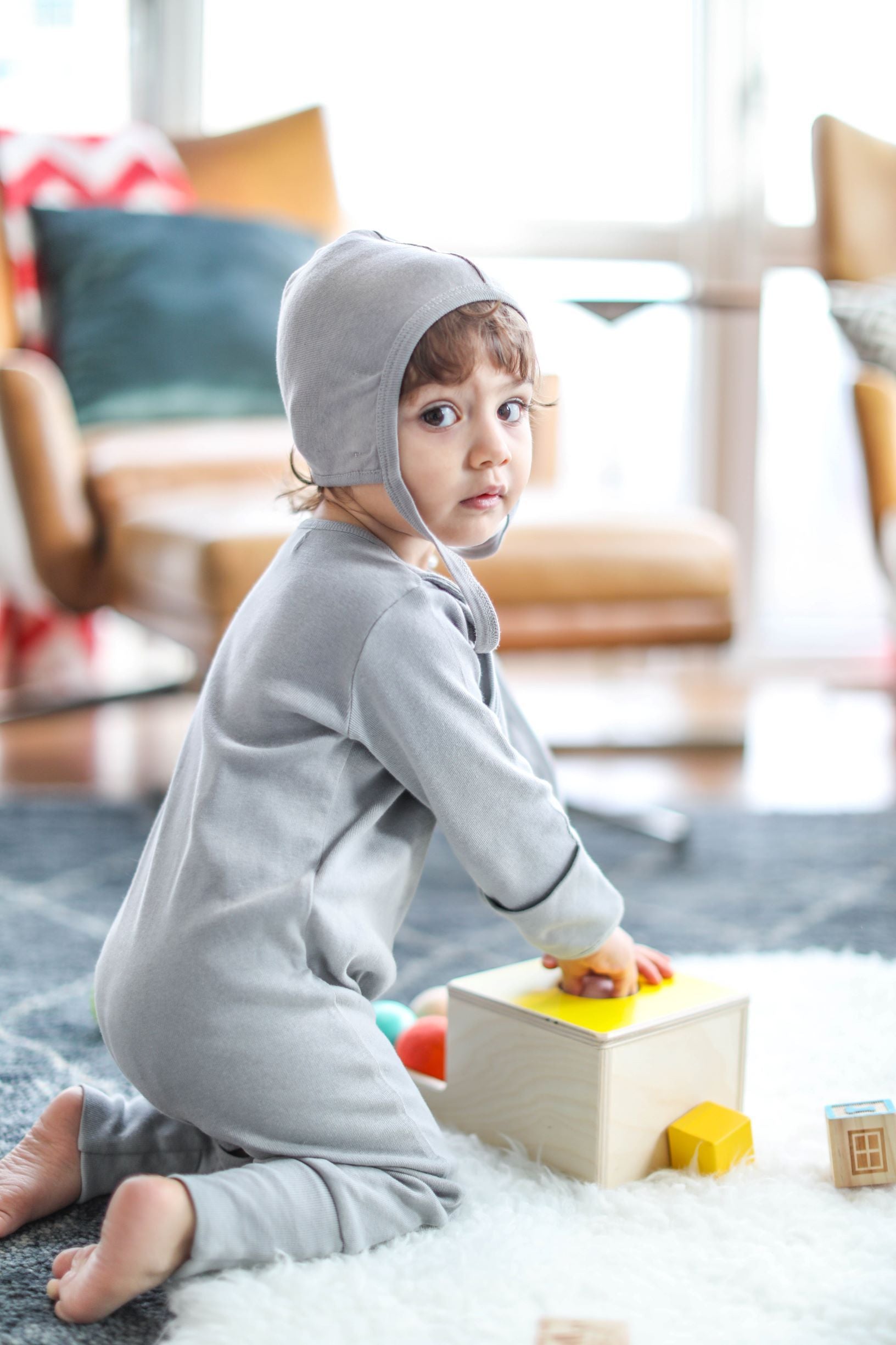 Gray smart footed one-piece with attachable bib made of organic cotton, featuring convertible feet and hand covers.