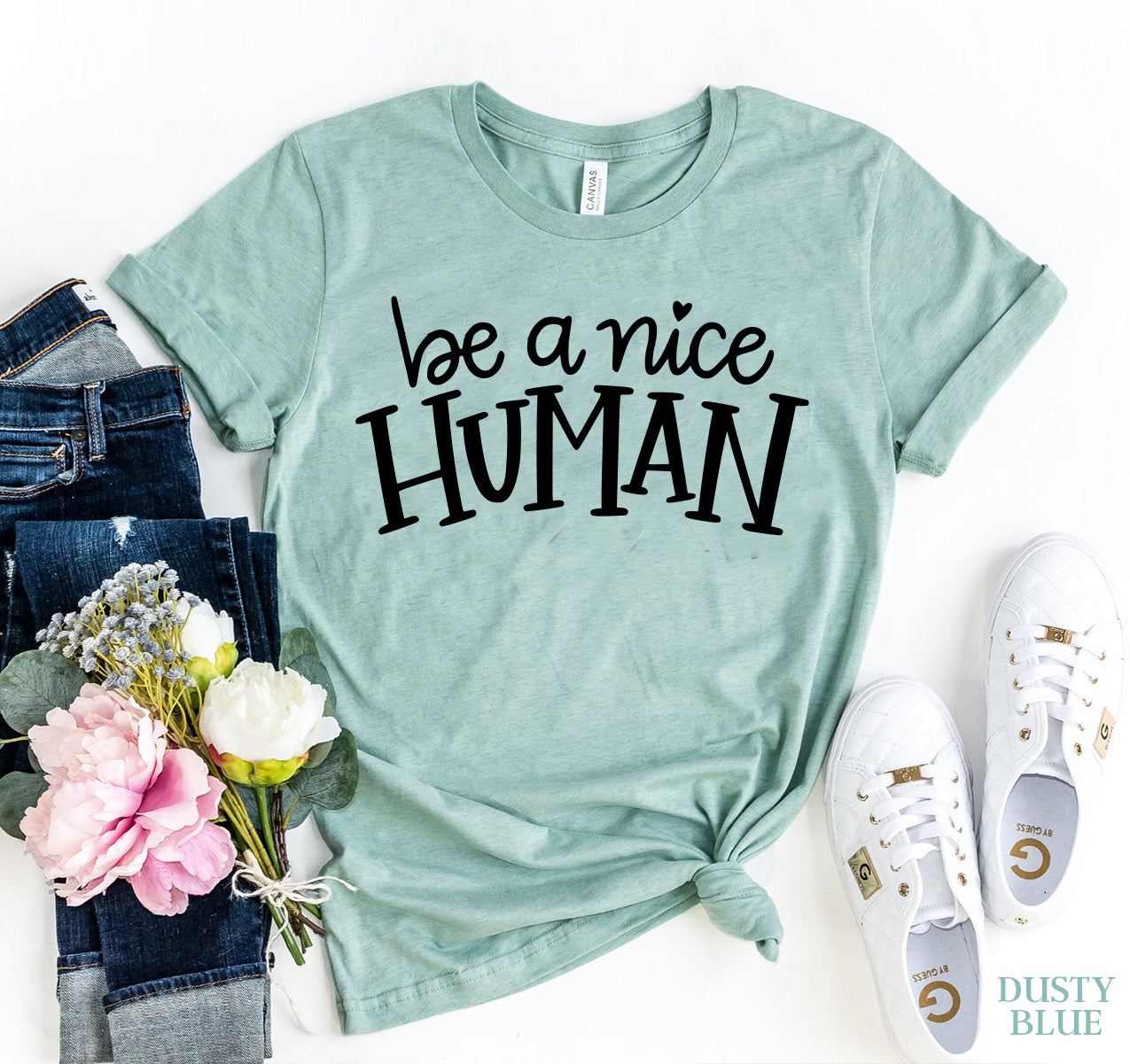 Light blue "Be A Nice Human" t-shirt with floral decor and casual shoes, emphasizing positivity.