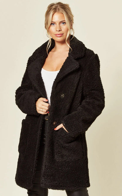 Oversized black teddy coat with stud button fastening and side pockets.